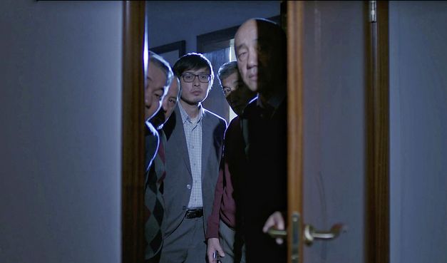 Filmstill aus „Akyn (Poet)“ von Darezhan Omirbayev. Fünf Männer stehen an einer geöffneten Tür und schauen in ein Zimmer. 
