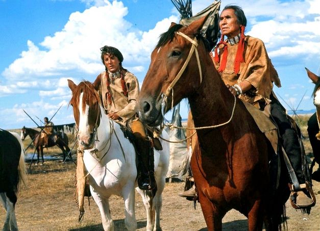 Film still from LITTLE BIG MAN: Two men in Indian dress sit on horses.