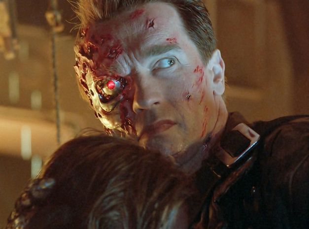 Film still from TERMINATOR 2: A man with a scarred, bloody face and a glowing red eye looks to the right.