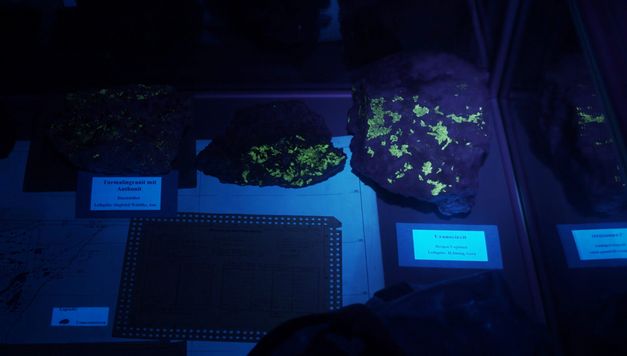 Filmstill aus dem Film "Sonne Unter Tage" von Mareike Bernien und Alex Gerbaulet. Fluoriszierende Steine von Schwarzlicht beleuchtet.