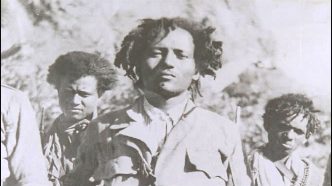 Historische Schwarzweißaufnahme von drei Personen in Uniform, die nebeneinander stehen und in die Kamera blicken.