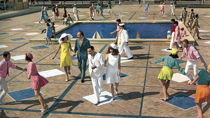 Filmstill from LES DEMOISELLES DE ROCHEFORT: Lots of smiling people dancing and running across a square. They are all wearing strikingly colourful or white clothes. In the centre is a water basin with miniature sailing boats.