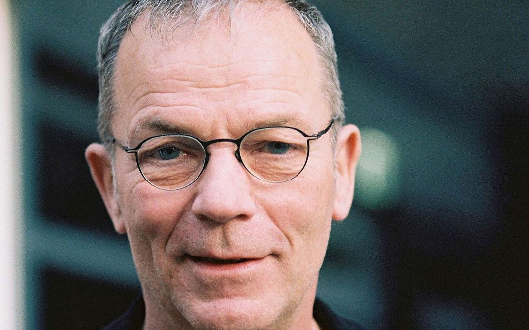 Portrait von Thomas Heise: Ein Mann mit kurzen grauen Haaren, einer Brille mit schmalem Rand. Er lächelt.