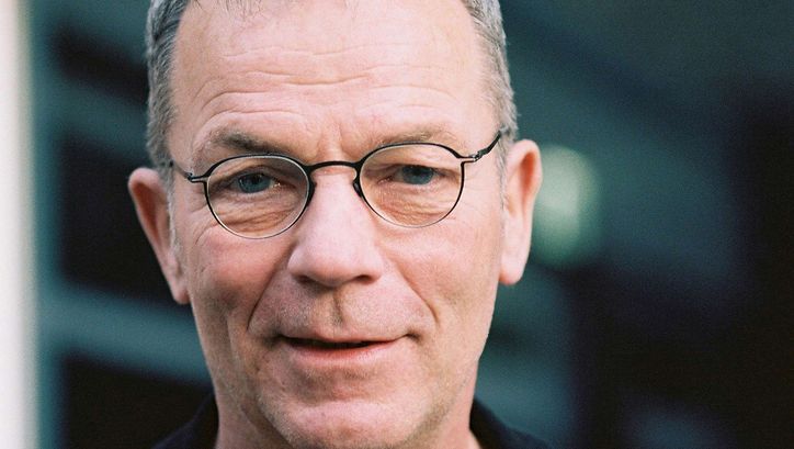 Portrait of Thomas Heise: A man with short grey hair and narrow-rimmed glasses. He is smiling.