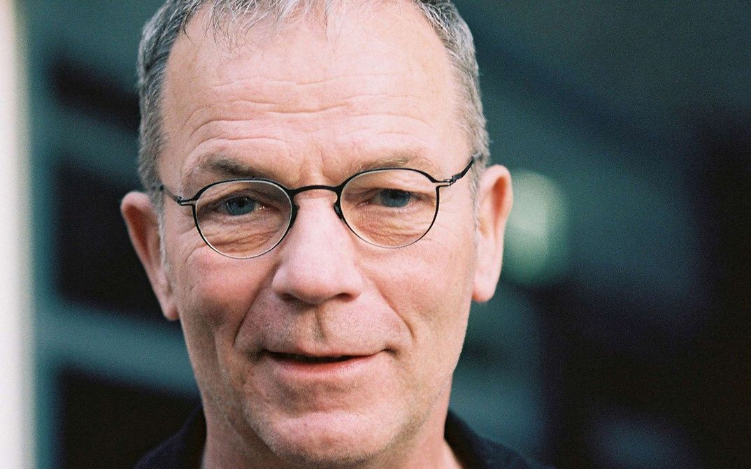 Portrait of Thomas Heise: A man with short grey hair and narrow-rimmed glasses. He is smiling.