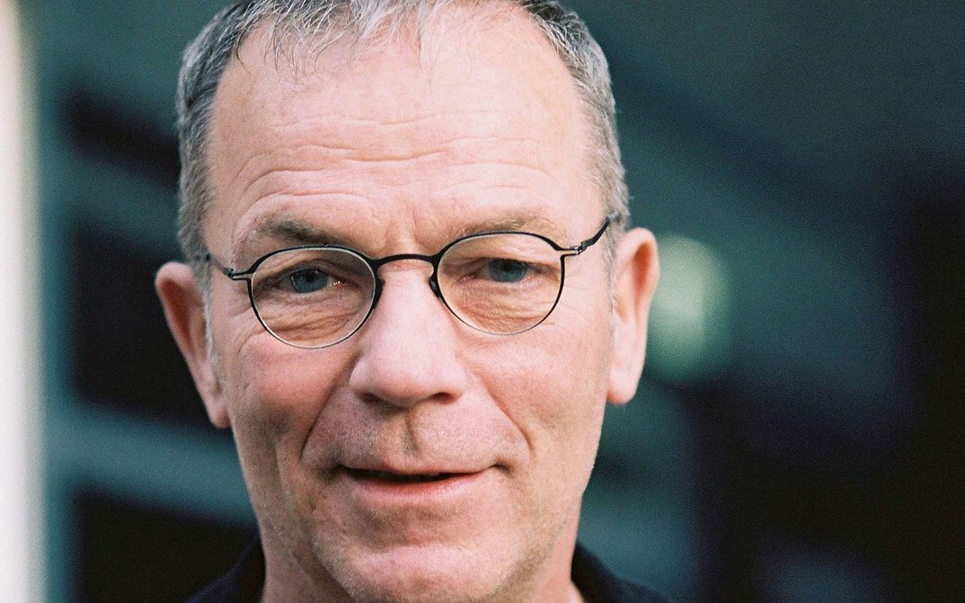 Portrait of Thomas Heise: A man with short grey hair and narrow-rimmed glasses. He is smiling.