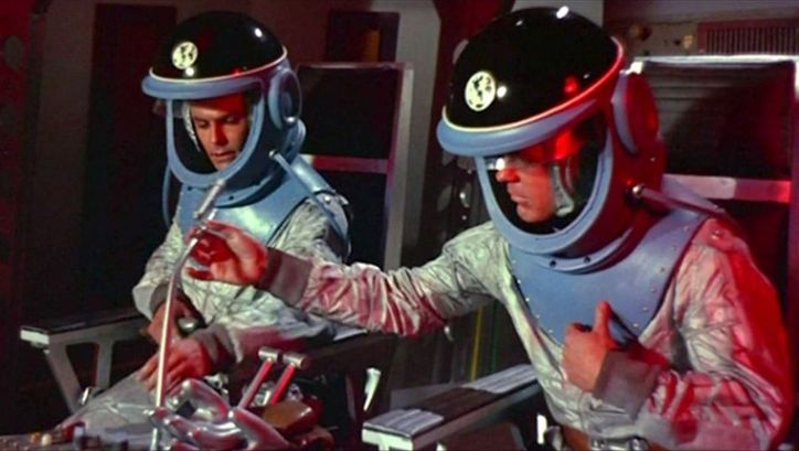 Filmstill aus DER HIMMEL RUFT: Zwei Astronauten mit Raumanzügen in einem Raumschiff.