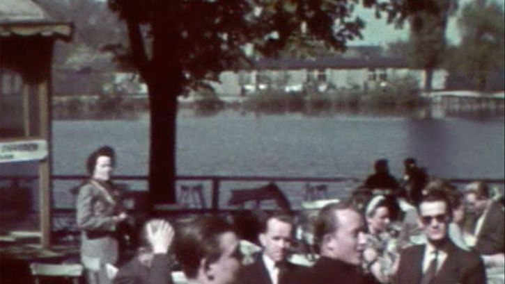 People sitting in a beer garden. Water in the background, the sun is shining.