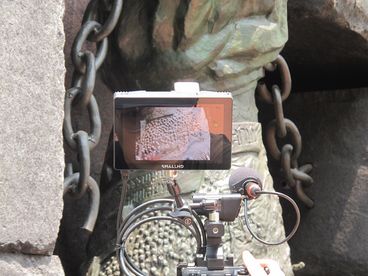 A behind-the-scenes shot of a camera monitor. On the monitor we see a detail shot of a textured statue.