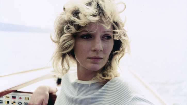 Filmstill aus DIE ALLEINSEGLERIN: Eine junge Frau mit lockigen, blonden Haaren steht am Bug eines Segelbootes.