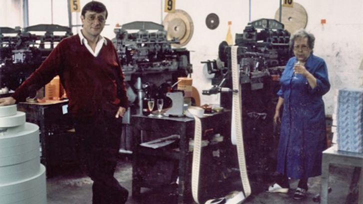 Filmstill aus BECKERBILLET: Ein Mann und eine Frau stehen zwischen Druckmaschinen, auf denen Kinobillets gedruckt werden.