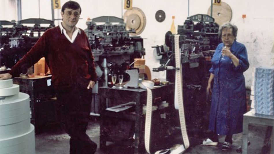 Filmstill aus BECKERBILLET: Ein Mann und eine Frau stehen zwischen Druckmaschinen, auf denen Kinobillets gedruckt werden.