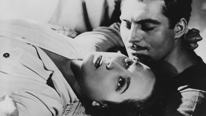 Film still from LYDIA: A woman is lying on a sofa, next to her a man is looking at her.