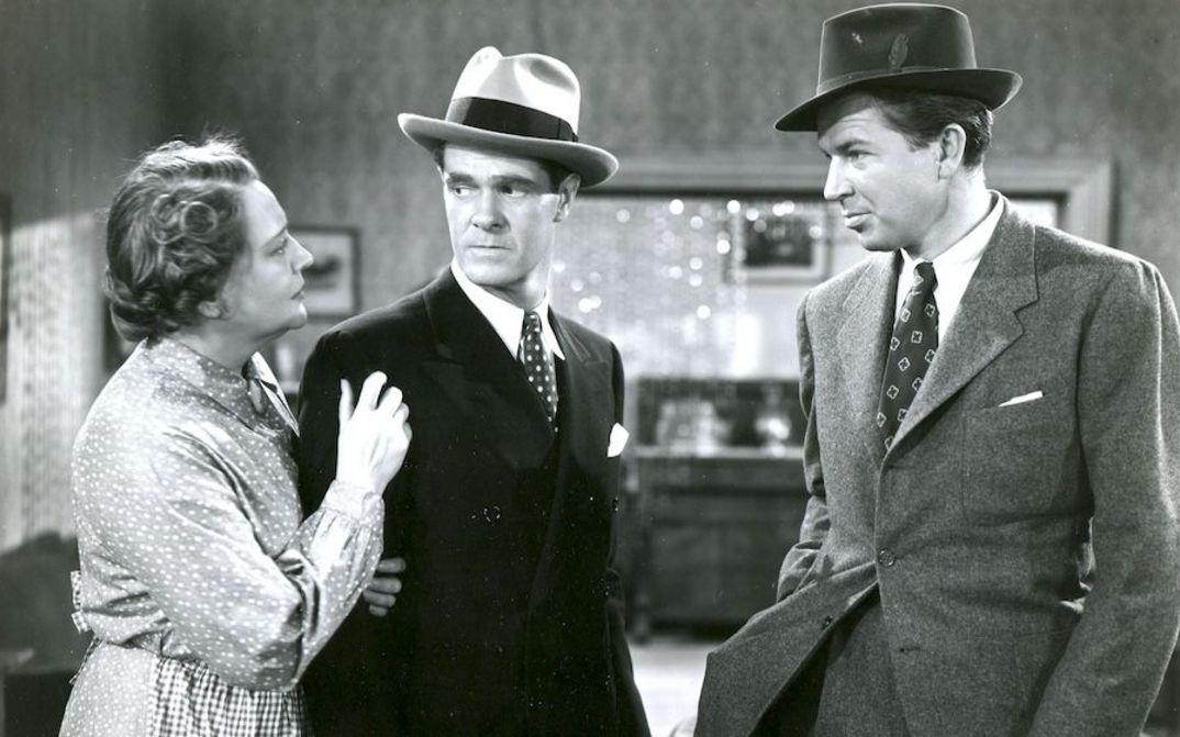 Filmstill aus GIRLS UNDER 21: Eine Frau und zwei Männer, beide Männer schauen zu ihr.