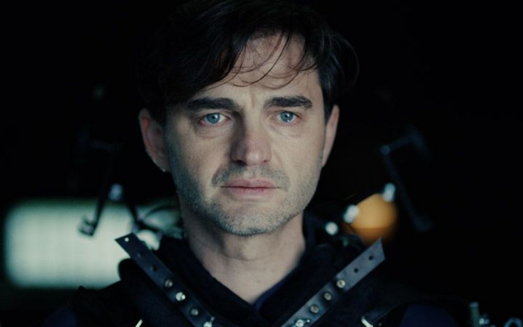 Close-up of the face of a man with blue eyes. He seems to be close to tears.