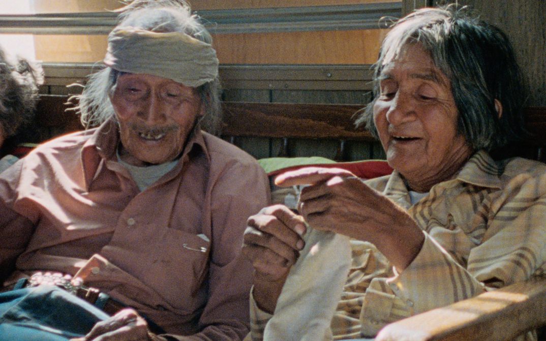 Film still from "Techqua Ikachi, Land – mein Leben" by Anka Schmid, James Danaqyumptewa and Agnes Barmettler. It shows an old man and an old woman sitting next to each other. The man has a bandage around his head.
