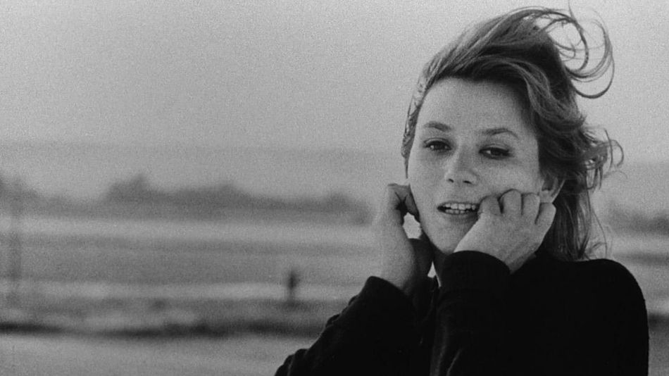 Filmstill aus LA JETÉE: Eine Frau mit vom Wind zerzausten Haar hält beide Hände an ihr Gesicht.