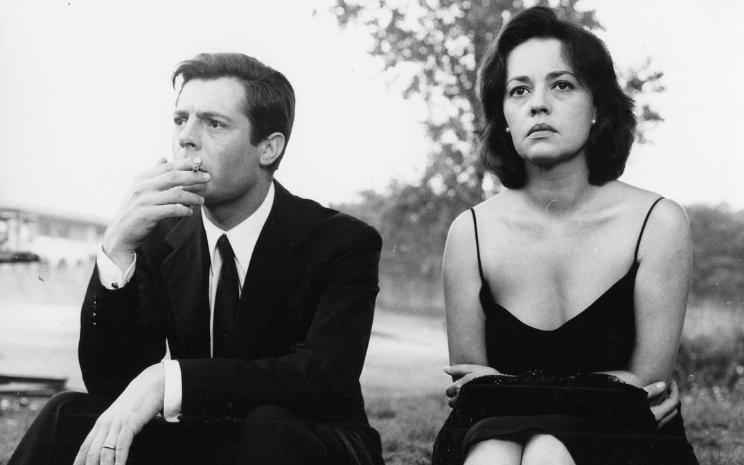 Filmstill aus LA NOTTE: Marcello Mastroianni und Jeanne Moreau sitzen in eleganter Kleidung nebeneinander und blicken in die Ferne.