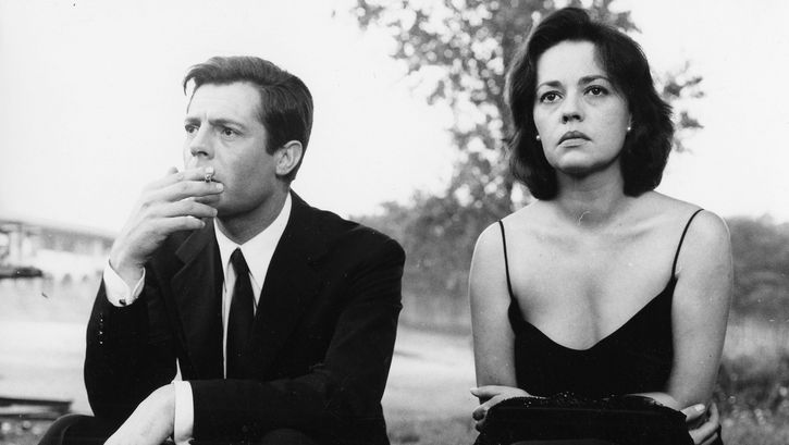 Film still from LA NOTTE: Marcello Mastroianni and Jeanne Moreau sit side by side in elegant clothes and look into the distance.