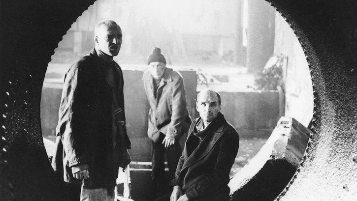 Film still from STALKER: Three men look through a circular opening in a building.