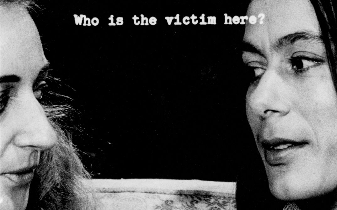 Film still from FILM ABOUT A WOMAN WHO...: The heads of two women looking at each other. Between them the writing: Who is the victim here?