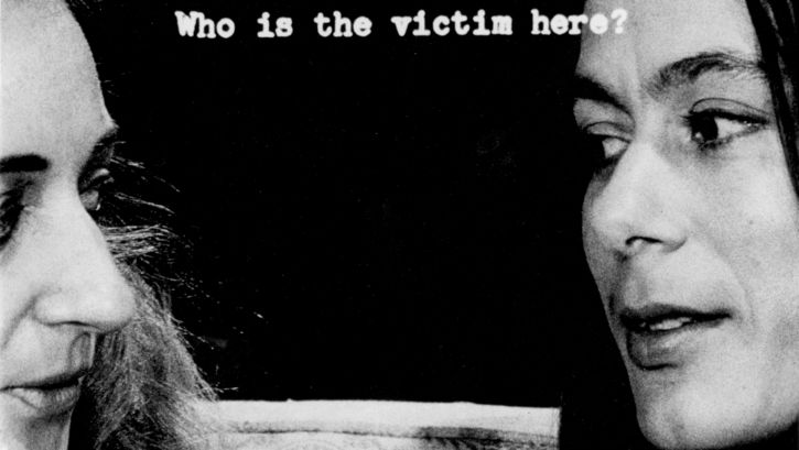 Filmstill aus FILM ABOUT A WOMAN WHO...: Die angeschnittenen Köpfe zweier Frauen, die sich anschauen. Zwischen ihnen der Schriftzug: Who is the victim here?