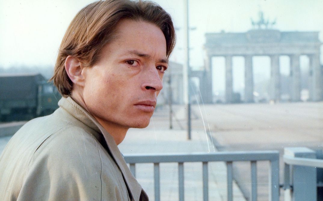 Filmstill aus DIE ARCHITEKTEN: Ein junger Mann mit nachdenklichem Gesichtsausdruck blickt zur Seite. Im Hintergrund ist das Brandenburger Tor zu sehen.