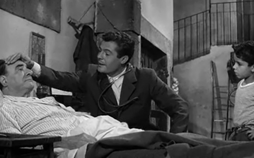 Filmstill aus IL MEDICO E LO STREGONE: Marcello Mastroianni als Arzt an einem Krankenbett.