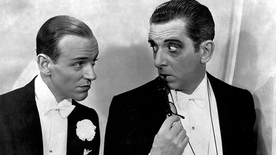 Film still from TOP HAT: Two men in evening dress look at each other.