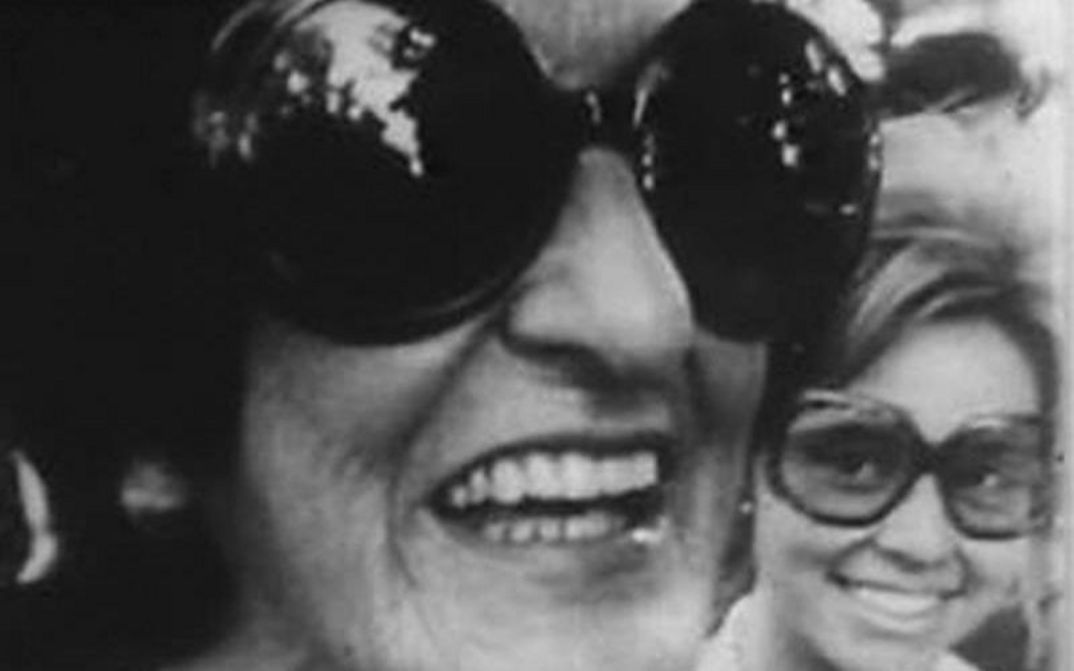 Film still from DESCOMEDIDOS Y CHASCONES: Two women with big sunglasses laugh into the camera.