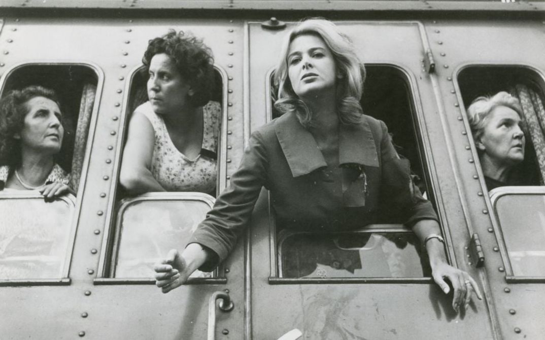 Film still from ESTATE VIOLENTA: Four women are leaning out of the train windows, side by side.