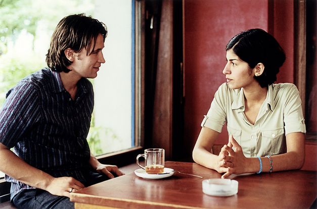 Filmstill aus „Der schöne Tag“ von Thomas Arslan. Ein junger Mann und eine junge Frau sitzen an einem Cafétisch und unterhalten sich. 