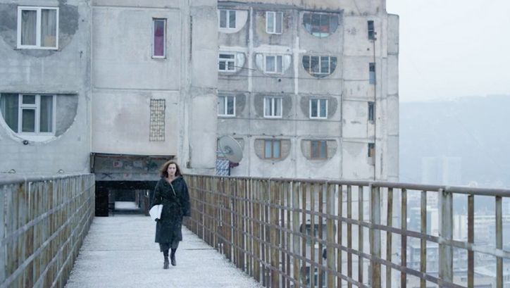 Filmstill aus SCARY MOTHER. Eine Frau läuft auf die Kamera zu, im Hintergrund ein großer Wohnblock.