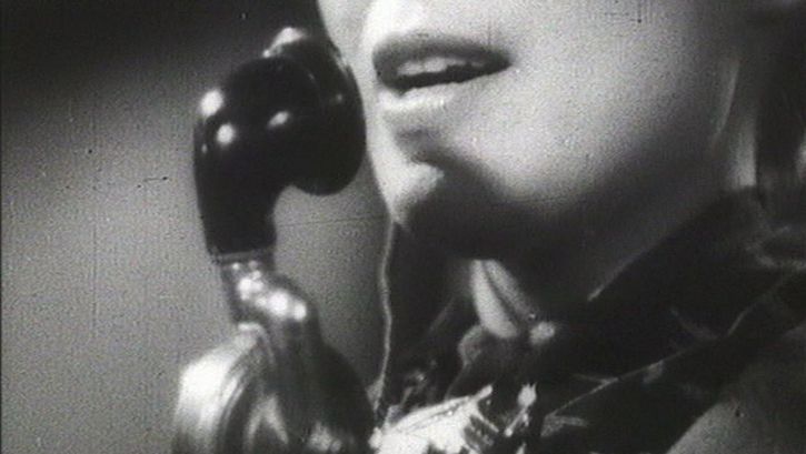 Filmstill aus ALLÔ BERLIN? ICI PARIS!: Das angeschnittende Gesicht einer Frau mit einem Telefonapparat.