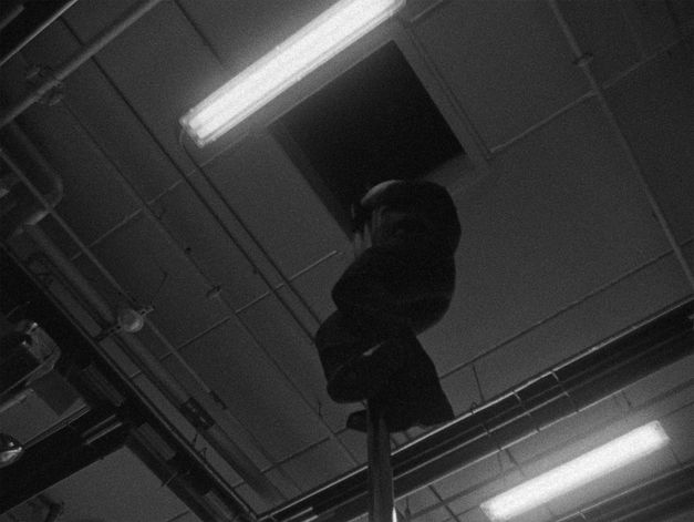 Filmstill from the Film "Fire Emergencies". A man slides down a fire pole.