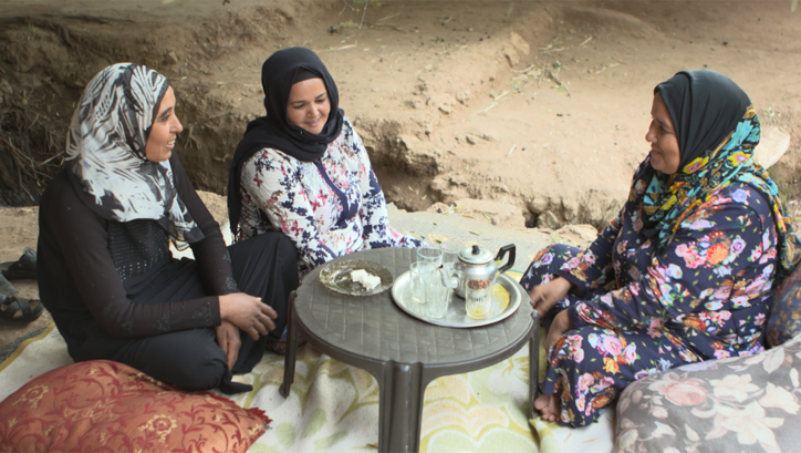 Filmstill aus SUSPENDED WIVES. Drei Frauen sitzen an einem niedrigen Tisch.