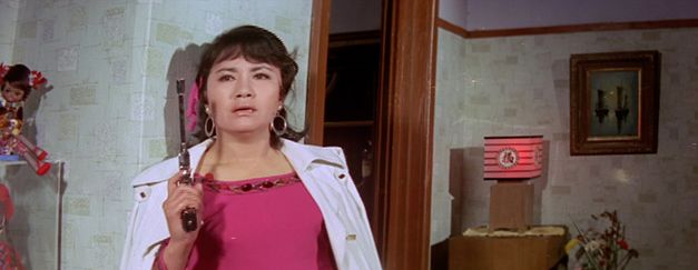 Film still from THE SENSE OF VIOLENCE by Mooyung Kim. It shows a slightly pixelated close-up of a woman with a pistol.