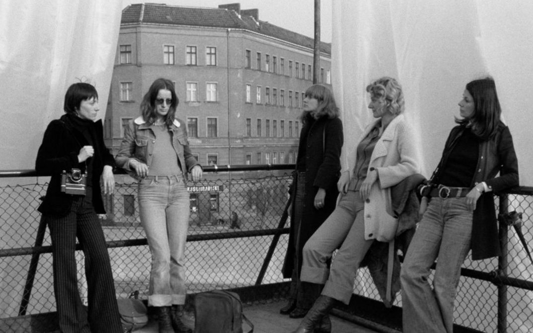Filmstill aus DIE ALLSEITIG REDUZIERTE PERSÖNLICHKEIT – REDUPERS. Fünf Frauen stehen auf der Terrasse eines Hauses.