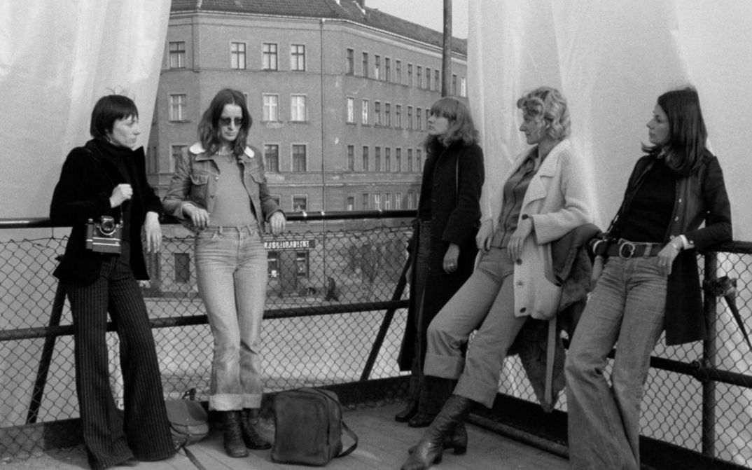 Filmstill aus DIE ALLSEITIG REDUZIERTE PERSÖNLICHKEIT – REDUPERS. Fünf Frauen stehen auf der Terrasse eines Hauses.