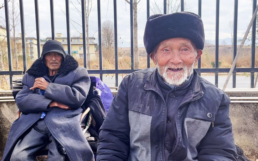 Film still from GUOCHANG by Nana Xu. The picture shows two elderly men in front of a fence.