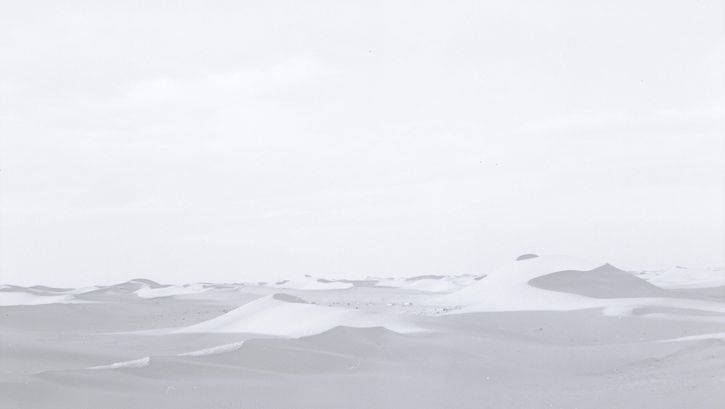 Filmstill aus FATA MORGANA: Eine Wüstenlandschaft in zarten schwarz-weiß-Farbtönen.