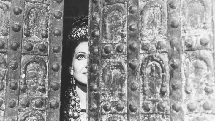 Filmstill aus MEDEA. Maria Callas als Medea blickt durch einen Türspalt.