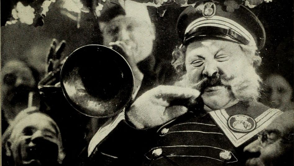 Film still from DER LETZTE MANN: An old man with a large mustache and a uniform is standing next to a trumpet player.