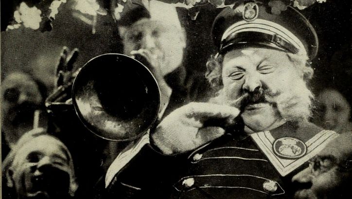 Filmstill aus DER LETZTE MANN: Ein alter Mann mit großem Schnurbart und Uniform steht neben einem Trompeter.