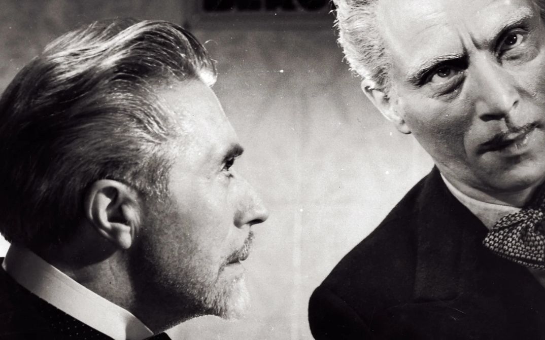 Filmstill aus LA FIN DU JOUR: Man sieht die Köpfe zweier Männer, der eine schaut den anderen an.