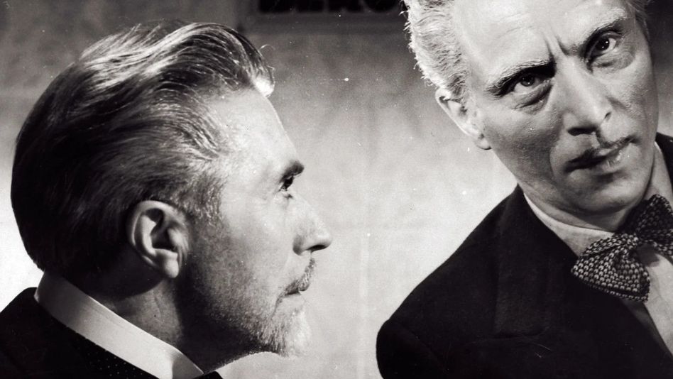 Filmstill aus LA FIN DU JOUR: Man sieht die Köpfe zweier Männer, der eine schaut den anderen an. 