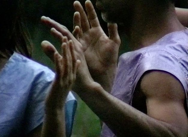 Still from the film "Afterwater" by Dane Komljen. A close-up of the hands and torsos of two standing bodies.