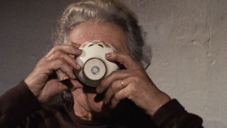 Filmstill aus O MOVIMENTO DAS COISAS: Eine Frau trinkt aus einer Tasse, die ein Teil ihres Gesichts verdeckt.