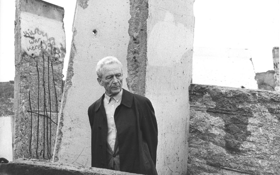Filmstill aus ICH WAR EIN GLÜCKLICHER MENSCH: Ein älterer Mann steht vor den Überresten der Berliner Mauer.