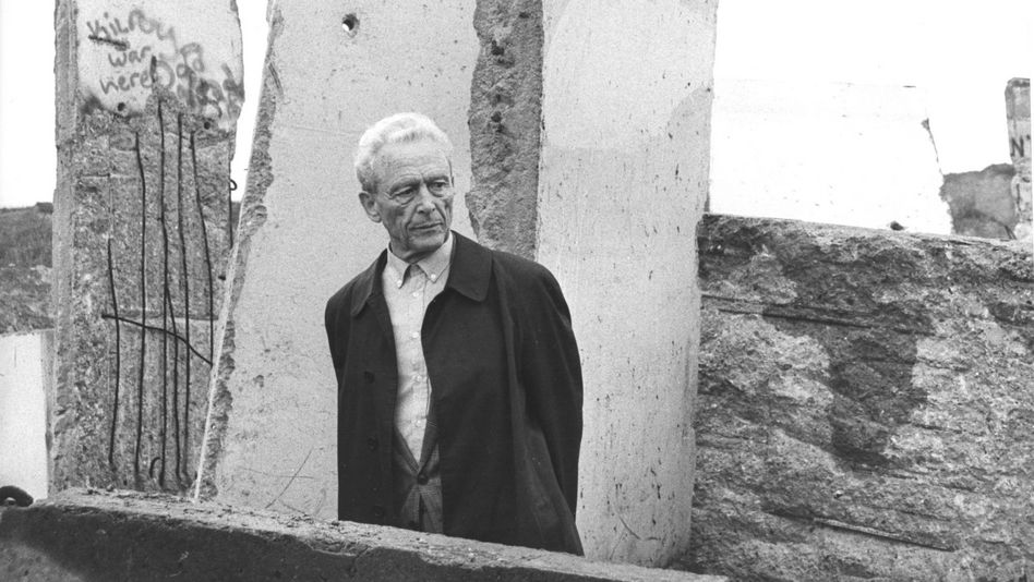 Filmstill aus ICH WAR EIN GLÜCKLICHER MENSCH: Ein älterer Mann steht vor den Überresten der Berliner Mauer.